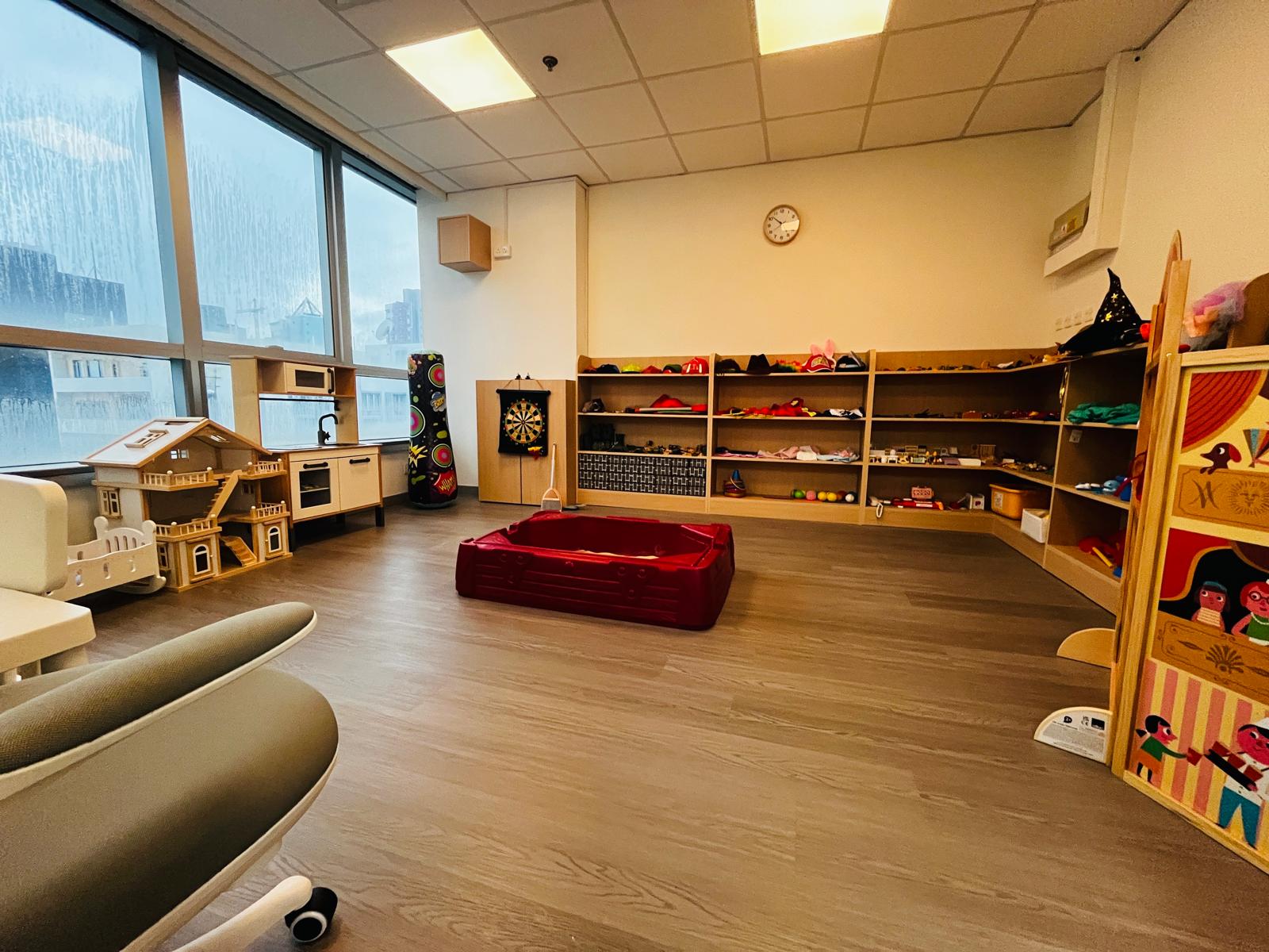 The play therapy room at the Jordan office — a dollhouse, sand tray and shelves of toys by a bright window